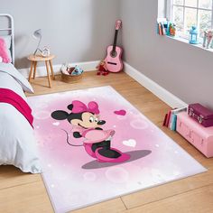 a bedroom with a pink bed and mickey mouse rug on the floor next to a guitar