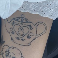 a woman's thigh with tattoos on her legs and a teapot tattoo in the shape of a heart