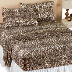 a bed with a leopard print comforter and two pillows on top of the bedspread