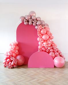 balloon arch with pink and silver balloons on the floor in front of a white wall