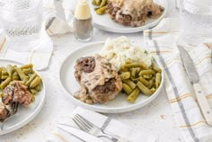 three plates with meat, green beans and mashed potatoes sitting on a table next to silverware