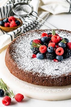 a chocolate cake topped with berries and powdered sugar