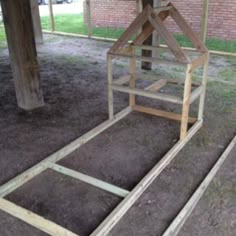 two wooden structures sitting in the dirt under a tree