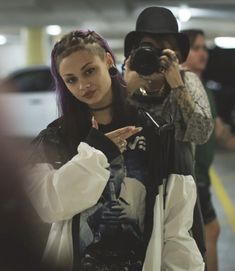 a man and woman taking pictures with their cell phones in an underground parking garage area