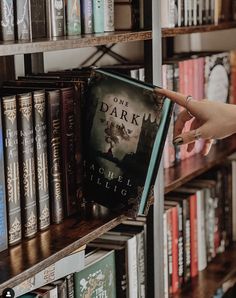 a person is reaching for a book on a shelf in a library filled with books