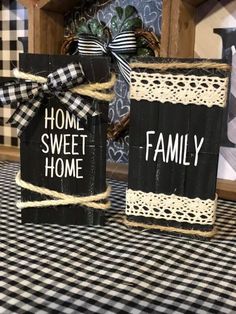 two black and white boxes with the words home sweet home on them sitting on a checkered tablecloth