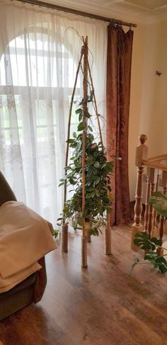 a living room filled with furniture next to a tall window covered in sheered curtains