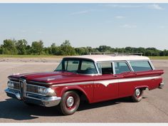 an old red and white station wagon parked in a parking lot