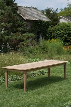 a wooden table sitting on top of a lush green field