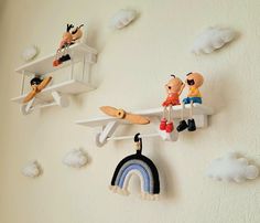 three toy figurines are hanging on the wall next to a rainbow and clouds