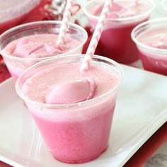 three cups filled with pink jello on top of a white plate next to candy canes