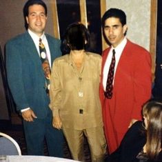 three people standing next to each other wearing suits and ties