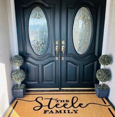 a black door with the words the steele family on it and two potted plants