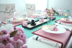 the table is set with pink flowers and place settings