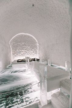 the inside of an ice hotel with snow on the floor and benches in the middle