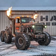 an old truck with flames on it parked in front of a building