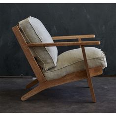 a wooden chair with a pillow on it's back and seat cushion in front of a black wall