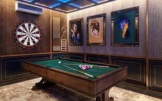 a room with a pool table, darts and pictures on the wall