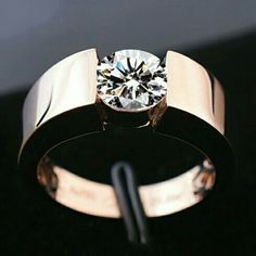 a close up of a ring with a diamond in it on a black surface next to a pair of scissors