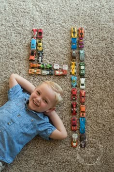 a little boy laying on the floor with his toy cars