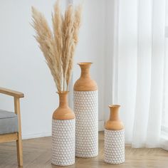 three ceramic vases sitting on top of a wooden floor