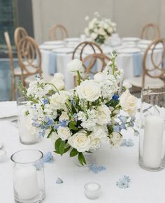 a vase filled with white flowers sitting on top of a table next to two candles