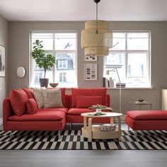 a living room with red couches and checkered rugs on the floor in front of two windows