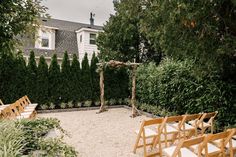 an outdoor ceremony setup with wooden chairs