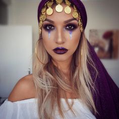 a woman with long blonde hair wearing a purple headband and gold jewelry on her face