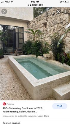 an outdoor hot tub in front of a stone wall with plants growing on the side