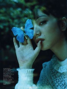 a woman holding a blue butterfly in her hand