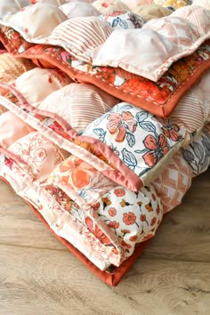 a pile of pillows sitting on top of a wooden floor next to a pillow case