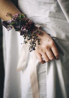 a close up of a person wearing a white dress with flowers on their arm and wrist