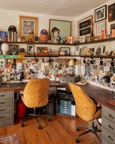 a desk with two chairs and many pictures on the wall above it in a home office