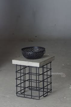 a black bowl sitting on top of a white table next to a metal wire basket