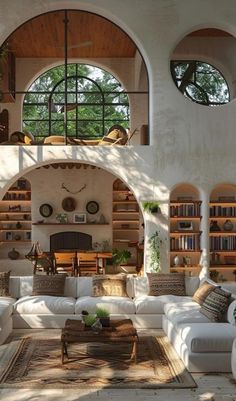 a living room filled with lots of furniture and bookshelves in front of two arched windows