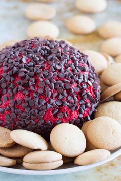 a red velvet cake surrounded by cookies and almonds on a white plate with blue background