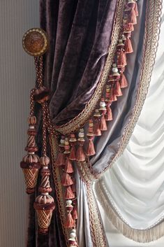 a curtain with tassels hanging from it's side in front of a window