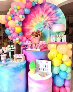 there are many balloons and cake on the table at this birthday party that is decorated with pastel colors