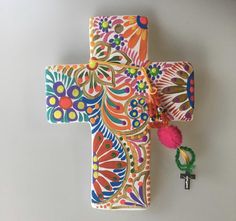 a colorful cross with a tassel hanging from it's side on a wall