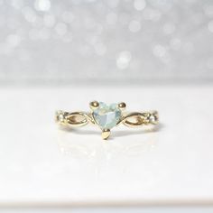 a gold ring with a heart shaped aqua blue topazte surrounded by small white diamonds