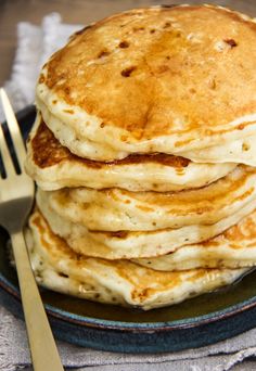 a stack of pancakes sitting on top of a blue plate with a fork and knife