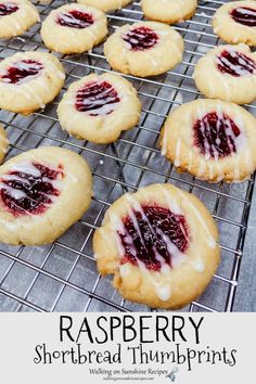 raspberry shortbread thumbprints are cooling on a wire rack with icing