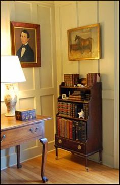 a room with a bookcase, lamp and pictures on the wall