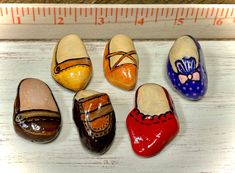 five painted shoes are lined up next to a ruler