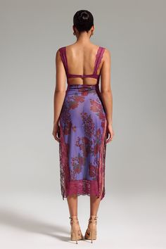 the back of a woman wearing a purple floral print dress with cutouts on it