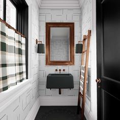 a bathroom with black and white tile, wood accents and a wooden ladder in the corner