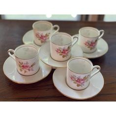 six tea cups and saucers with pink flowers on them sitting on a wooden table