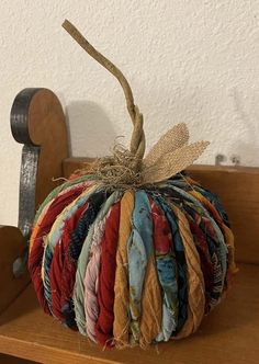 a small patchwork pumpkin sitting on top of a wooden shelf