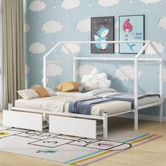 a white bed sitting on top of a wooden floor next to a wall with clouds painted on it